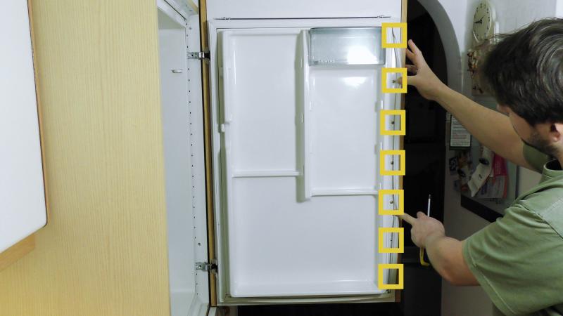 Seitliche Schrauben der Kühlschrankverkleidung ausdrehen Seitliche Schrauben der Kühlschrankverkleidung ausdrehen