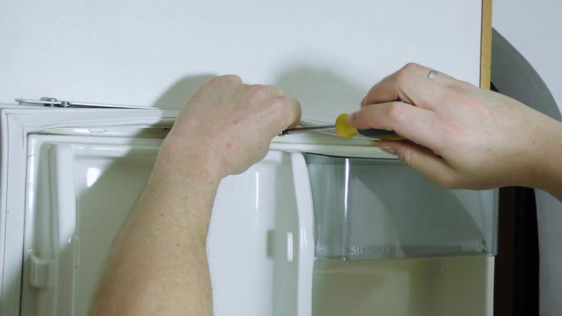 Obere Schrauben der Kühlschrankverkleidung als letztes entfernen Obere Schrauben der Kühlschrankverkleidung als letztes entfernen